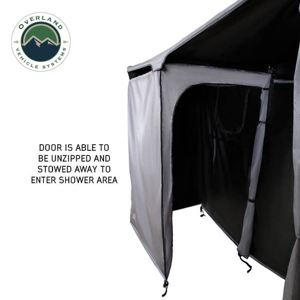 Image of a close-up of an OVS HD Nomadic 2-person car-side shower and privacy room showing the unzipped door panel stowed open for shower access, grey exterior and black interior fabric displayed on a white background.