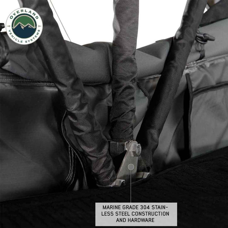 Image shows a close-up of the marine-grade 304 stainless steel construction and hardware of an Overland Vehicle Systems product, likely a rooftop tent or awning mechanism. Black straps and grey fabric are also visible, suggesting a durable outdoor equipment design