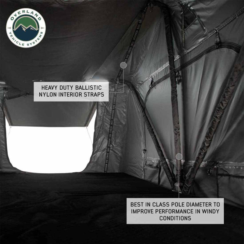Image of the interior of an Overland Vehicle Systems Nomadic Standard rooftop tent, showing the heavy-duty ballistic nylon interior straps and best-in-class pole diameter for improved performance in windy conditions. The floor is black, and a window opening is visible on the left side