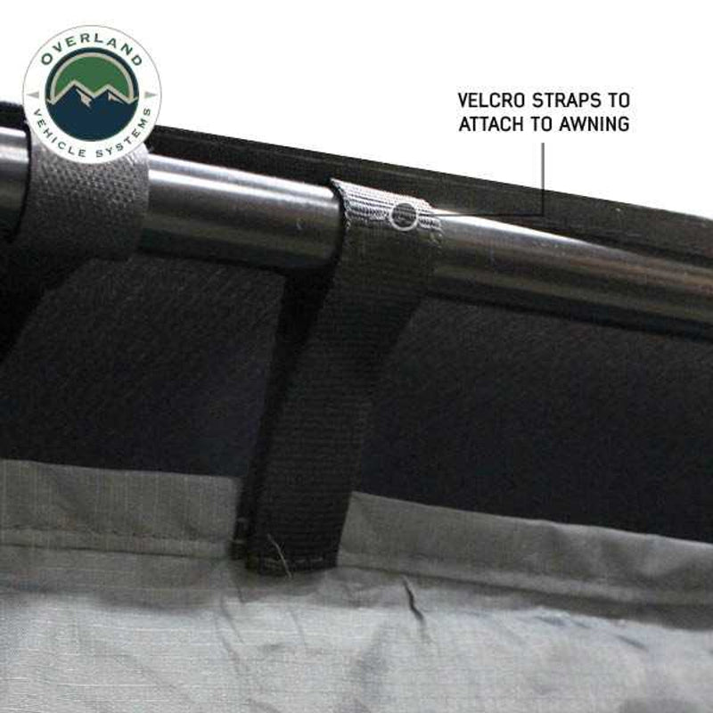 Image of a close-up of a vehicle awning room enclosure showing black Velcro straps wrapped around an awning support bar to attach the fabric panel, displayed in detail on a white background.