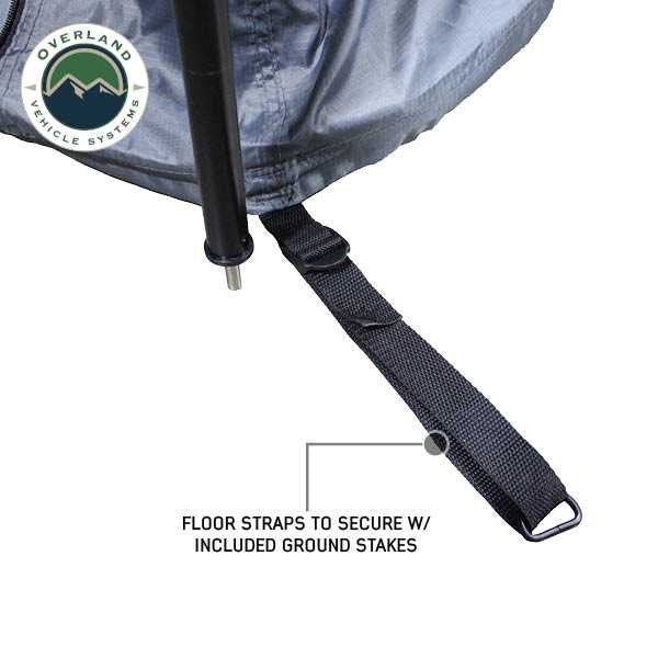 Image of a close-up of a vehicle awning room enclosure corner showing a black floor strap and support pole, designed to secure the enclosure with ground stakes, displayed on a white background.