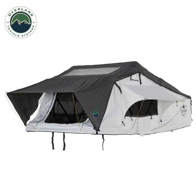 Image of a white Nomadic Extended rooftop tent with a dark grey roof cover and extended awning, fully set up, shown from a slightly elevated front angle on a white background
