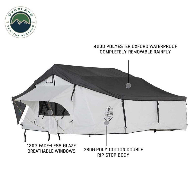 Image of a white Nomadic Extended rooftop tent with a dark grey 420D Polyester Oxford waterproof and completely removable rainfly, featuring 120G fade-less glaze breathable windows and a 280G poly cotton double rip stop body, fully set up and extended, viewed from the front and side on a white background
