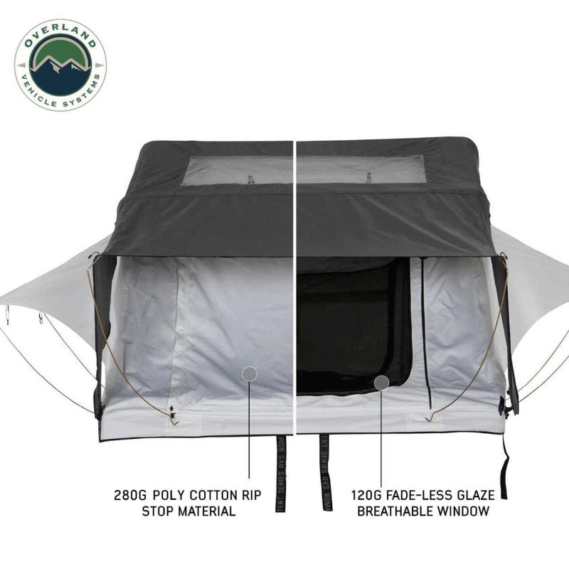 Image of a split view of a Nomadic rooftop tent, showcasing the 280G poly cotton rip stop material on one side and a 120G fade-less glaze breathable window on the other, all with a dark grey rainfly overhead, on a white background