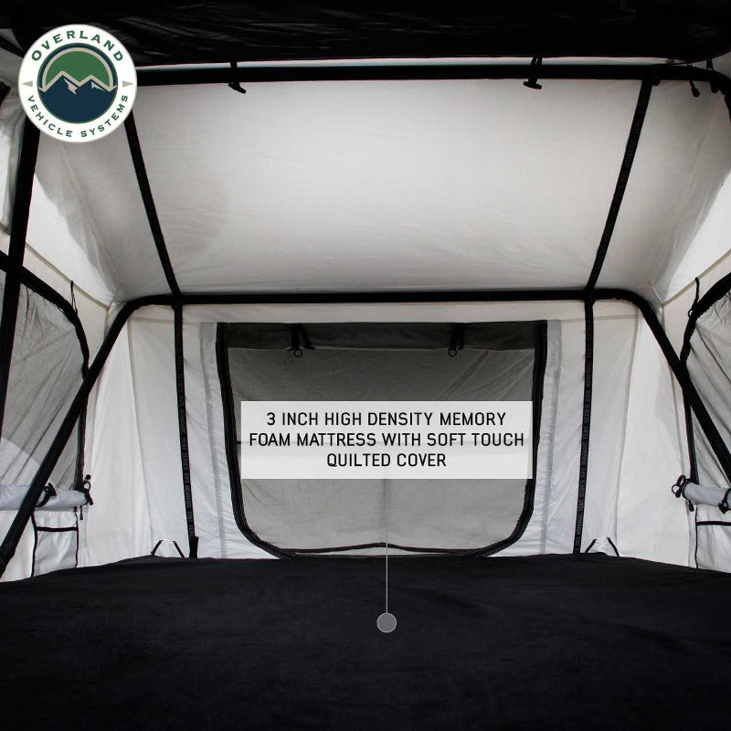 Image of the interior of a Nomadic rooftop tent, showcasing a 3-inch high-density memory foam mattress with a soft-touch quilted cover, along with the tent's white walls and black support poles