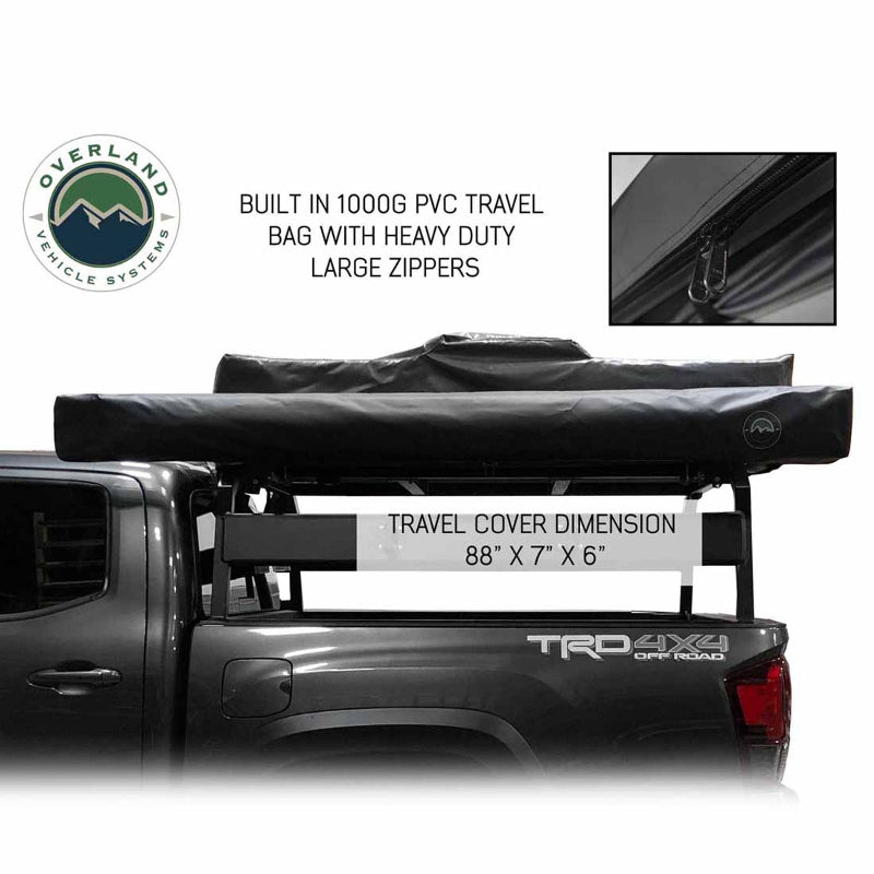 Image of the OVS Nomadic Awning in its black travel cover, mounted on a truck bed rack over a grey pickup truck. The image includes text with the travel cover dimensions and a close-up inset of the heavy-duty zipper
