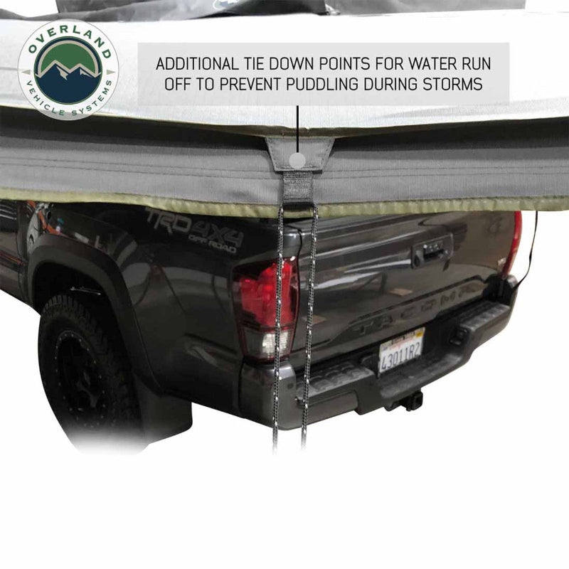 Image of the OVS Nomadic Awning showing an additional tie-down point for water runoff, attached to the back of a pickup truck to prevent puddling during storms