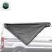 Image of the OVS Nomadic Awning partially deployed on the side of a white van, showing the dark grey fabric rolled out in a triangular shape