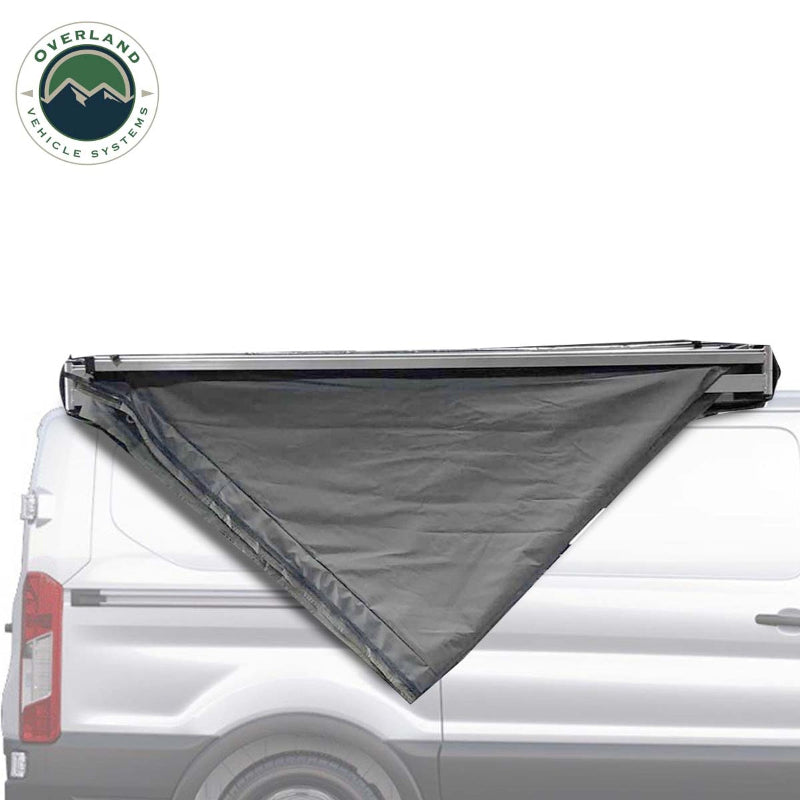 Image of the OVS Nomadic Awning partially deployed on the side of a white van, showing the dark grey fabric rolled out in a triangular shape
