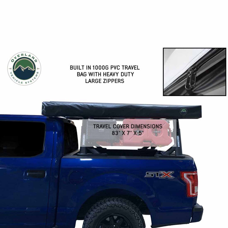 A Nomadic Awning is shown on the top of a blue pickup truck in a black, sealed PVC travel bag. The image also highlights the heavy-duty zippers of the travel bag with a close-up inset and notes the travel cover dimensions: 83" x 7" x 5"