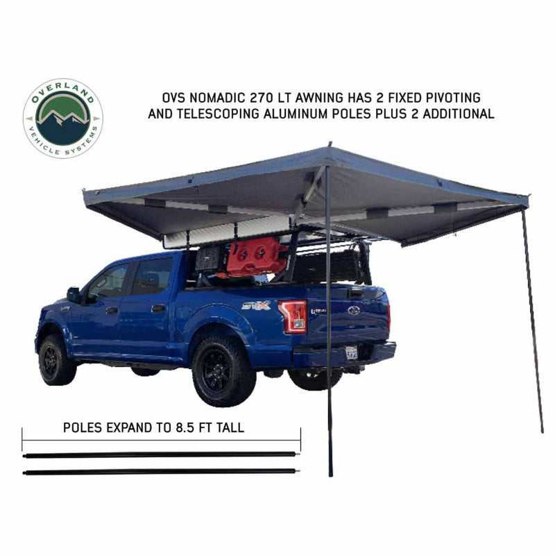 Image of the Overland Vehicle Systems Nomadic 270 LT Awning fully deployed on a blue Ford F-150. The image highlights the two fixed pivoting and telescoping aluminum poles that expand to 8.5 feet tall on a white background