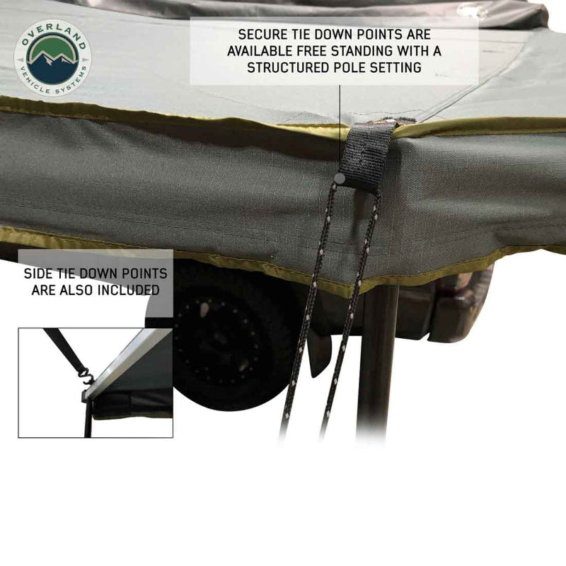 Image of the tie-down points on the Overland Vehicle Systems Nomadic 180 Awning, showing both the main corner tie-down and a closer inset image of the side tie-down. The text highlights that the awning can be used free-standing or with a structured pole setting