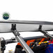 Image of the OVS Nomadic 180° Awning mounting brackets, including black L-shaped and slotted flat brackets, attached to a vehicle's roof rack with other gear visible