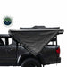 Image of the OVS Nomadic 180° Awning partially deployed on the side of a gray pickup truck, showcasing the black fabric with a side profile view on a white background
