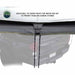 Image of a gray awning with a tie-down point and an attached cord, designed for water runoff. The text "ADDITIONAL TIE DOWN POINTS FOR WATER RUN OFF TO PREVENT PUDDLING DURING STORMS" is visible above the tie-down
