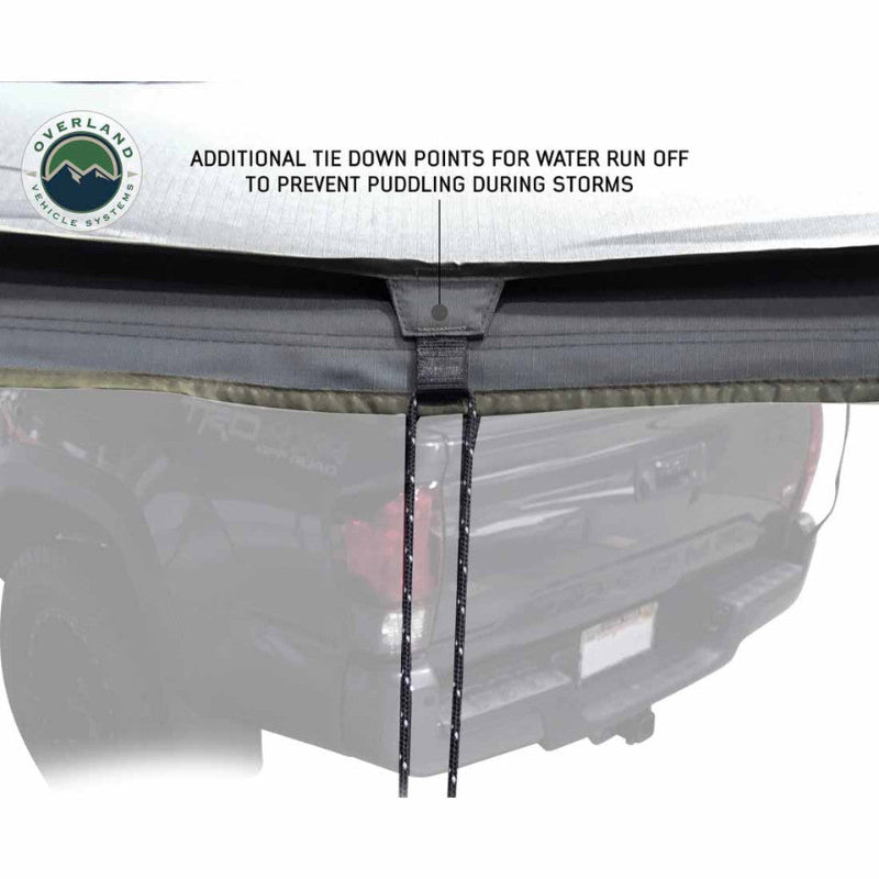 Image of a gray awning with a tie-down point and an attached cord, designed for water runoff. The text "ADDITIONAL TIE DOWN POINTS FOR WATER RUN OFF TO PREVENT PUDDLING DURING STORMS" is visible above the tie-down
