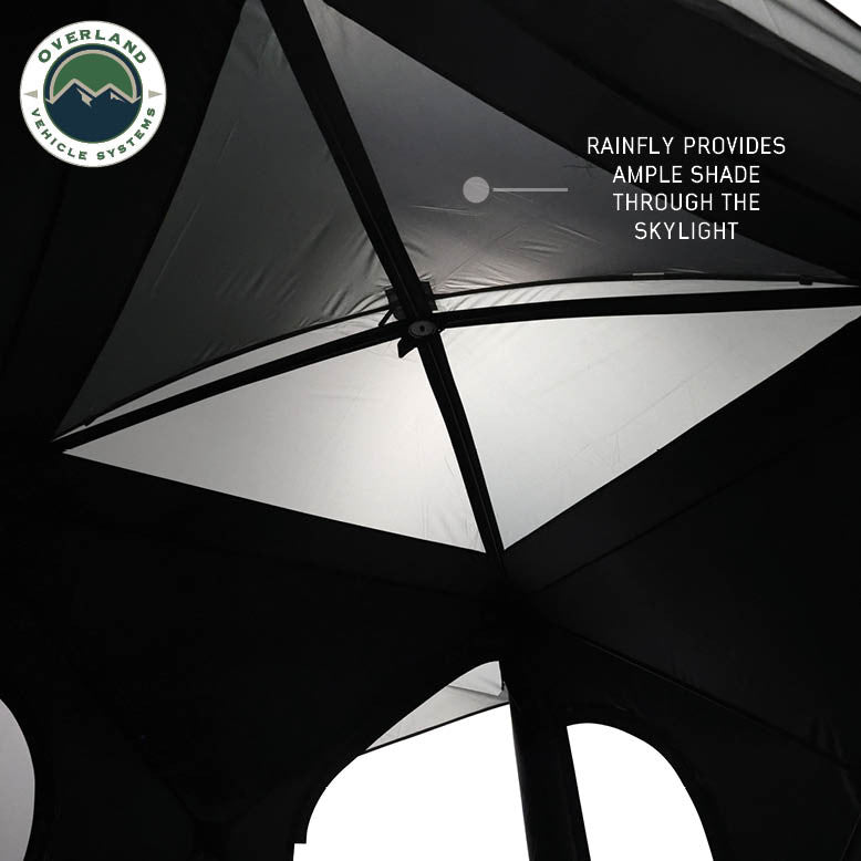 Image of OVS hub-style camping tent interior skylight showing rainfly providing shade and light diffusion, black and gray fabric panels, upward angled view on a neutral background.