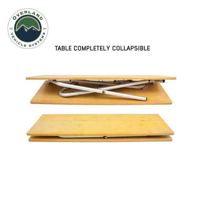 Image of OVS Kick It bi-fold camp table shown fully collapsed with folding legs tucked between bamboo wood panels, compact portable design displayed on a white background.