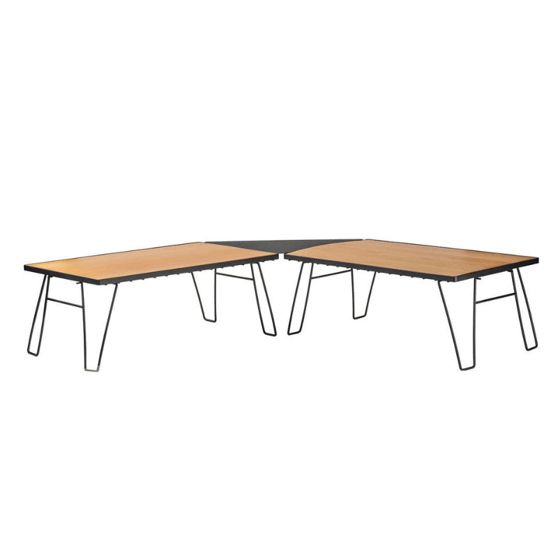 Image of modular folding camp table system with light wood tabletops and black metal legs arranged in an angled multi-panel layout, front and side view on white background.