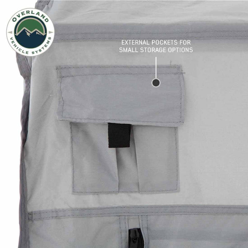 A close-up of the OVS ground tent's side, showing its external storage pocket. The image highlights the external pockets for small storage options, which are a lighter gray material