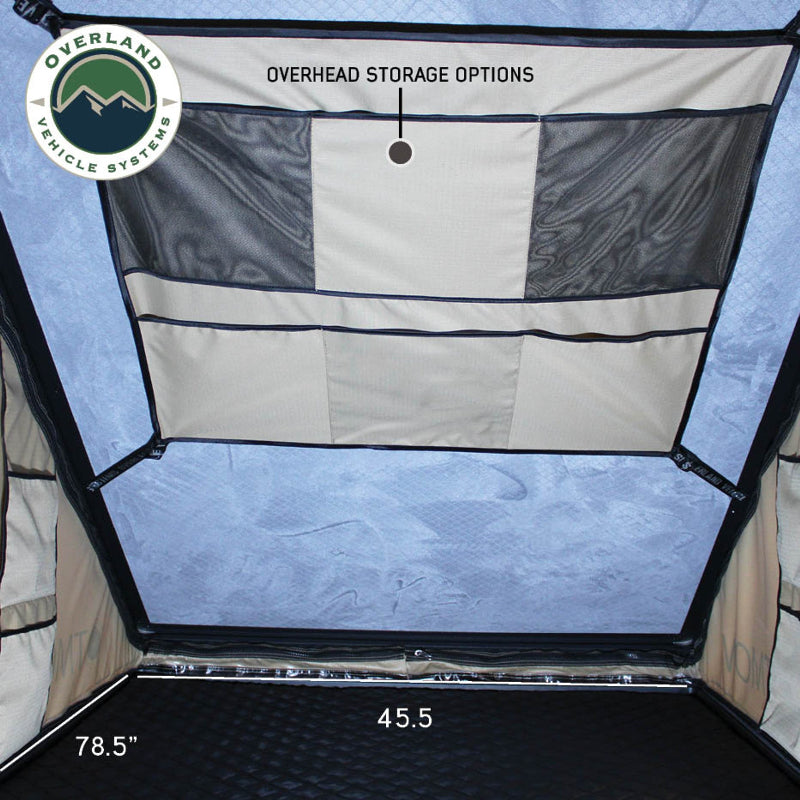 Image displaying a close-up of a heavy-duty nylon strap with grab handles, designed to simplify the closing of an Overland Vehicle Systems tent. The strap is black and shown against the beige tent fabric
