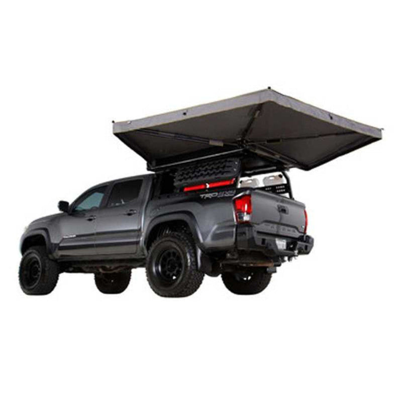 Image of a gray pickup truck, equipped with a roof rack and an open, gray awning extending from the side, on a white background.