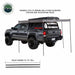 Image of a gray pickup truck with a Nomadic 270 LTE Awning fully extended and supported by four fixed aluminum pivoting and telescoping poles, which expand to 7.5 feet tall.