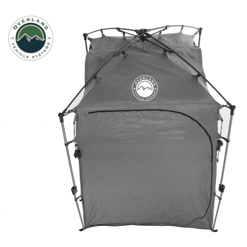 Image of a portable privacy shower tent fully assembled, dark gray fabric with zippered door and reinforced frame structure, straight front view on white background.
