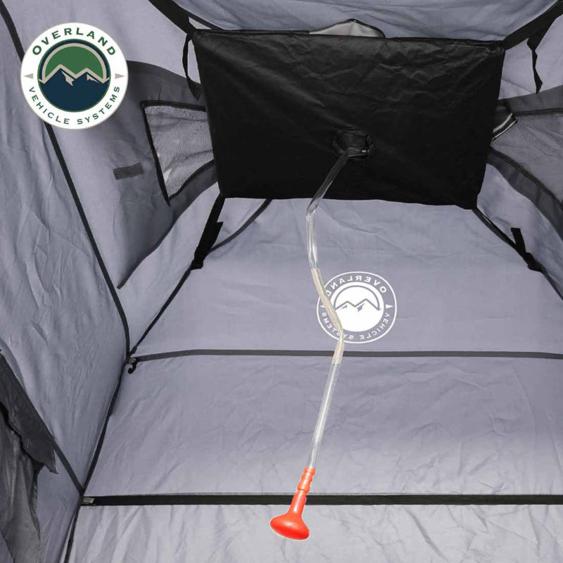 Image of a portable privacy shower tent interior showing waterproof floor, hanging shower bag holder with drain hose, and enclosed gray fabric walls, top-down interior view.