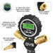 An image showcasing a close-up of the Overland Vehicle Systems (OVS) D.T.D. digital tire deflator gauge. The central feature is a black 3-inch circular dial with a heavy-duty rubber protective cover, displaying a green illuminated digital reading of "30.0 PSI." Below the gauge, anti-rust brass quick connect US fittings are visible. Insets highlight "QUICK CONNECT US FITTINGS" and "ANTI-RUST BRASS COMPONENTS." The text describes it as an "OVERSIZED DIGITAL DEFLATOR AND GAUGE WITH ILLUMINATED DISPLAY."