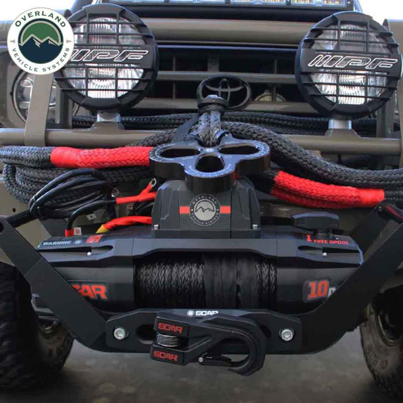 Overland Vehicle Systems SCAR Synthetic Rope Winch mounted on the front bumper of a gray Toyota Land Cruiser. The image shows the winch and its attached accessories, including a shackle, in a real-world application