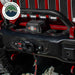 Image of an Overland Vehicle Systems (OVS) SCAR winch installed on a red Jeep Wrangler's front bumper, with the hook and strap connected to the fairlead. The winch is black with red accents and the Jeep is on a rocky, off-road surface