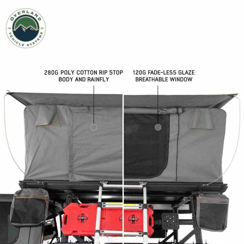 Image detailing the features of a dark grey rooftop tent, highlighting its 280G Poly Cotton Rip Stop body and rainfly, and a 120G Fade-Less Glaze breathable window, with camping gear including a red fuel can and ladder visible below. The "Overland Vehicle Systems" logo is in the top left corner, all on a white background