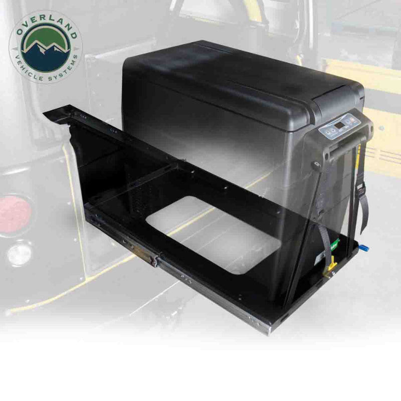 Image of portable electric refrigerator mounted on a heavy-duty sliding tray, black fridge unit with pull-out steel platform partially extended, angled front and side view on white background.