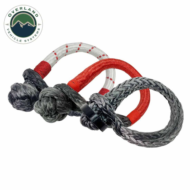 Image of two soft shackles, one charcoal with red and white striped sleeving and one gray with red sleeving, intertwined on a white background with the "Overland Vehicle Systems" logo.