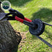 Image of a soft shackle, with red protective sleeving, connected to a tree saver strap wrapped around a tree trunk, and threaded through a black recovery ring, with grass in the background and the "Overland Vehicle Systems" logo.