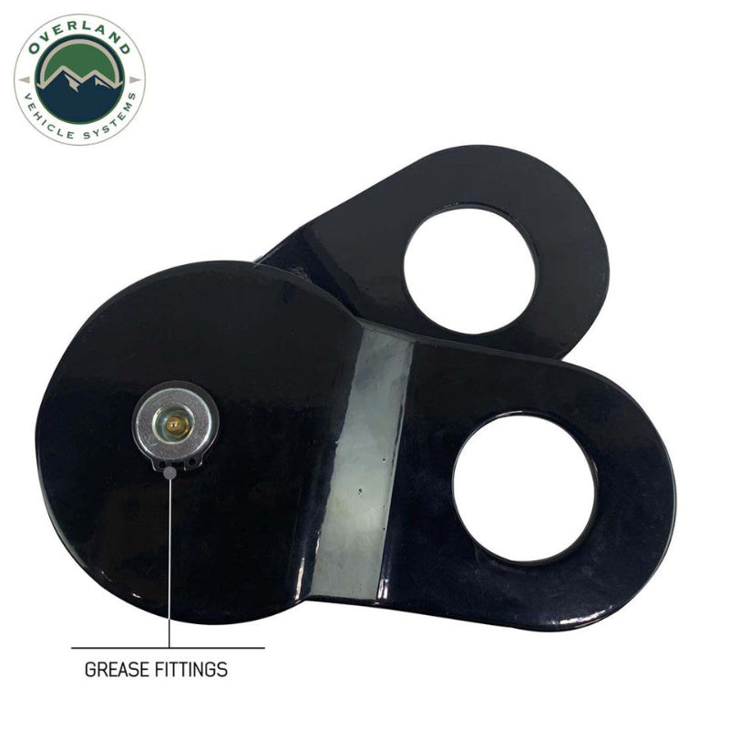 Image of Overland Vehicle Systems standard snatch block featuring grease fittings and dual mounting holes, black heavy-duty recovery pulley shown in angled top view on white background.