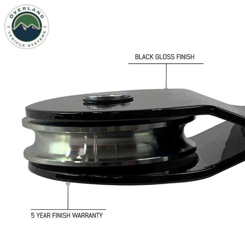 Image of Overland Vehicle Systems standard snatch block close-up showing black gloss finish pulley wheel and steel housing with 5-year finish warranty callout, side detail view on white background.