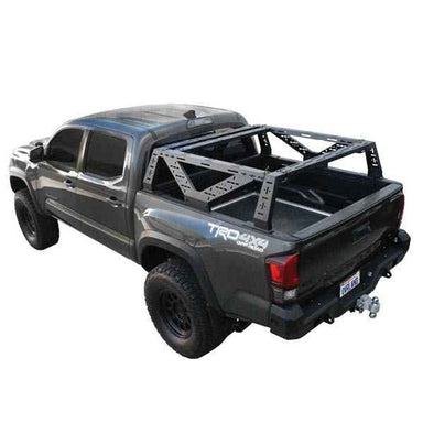 Image of Overland Vehicle Systems mid-height rack mounted on a black pickup truck, side view showing the sturdy metal frame and open truck bed, on a white background