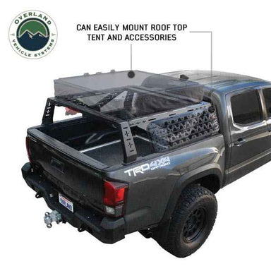 Image of Overland Vehicle Systems mid-height rack mounted on a black pickup truck, showing the rack's capability to easily mount a roof top tent and accessories, with a clear view of the truck bed and rugged outdoor background