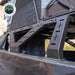 Image of a close-up view of the heavy-duty support legs of a mid-height rack for a pickup truck, showcasing its robust black frame, positioned to securely hold a roof top tent, set against a rugged desert backdrop