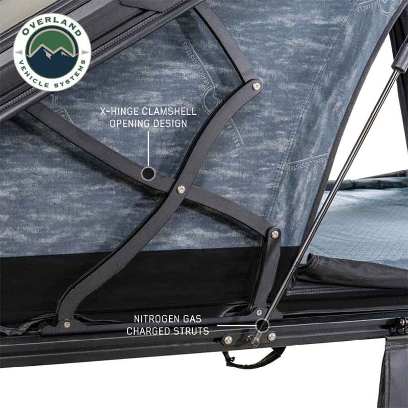 Image of Overland Vehicle Systems Lhotse rooftop tent featuring an X-hinge clamshell opening design and nitrogen gas charged struts, close-up view of the structure with blue fabric on a white background