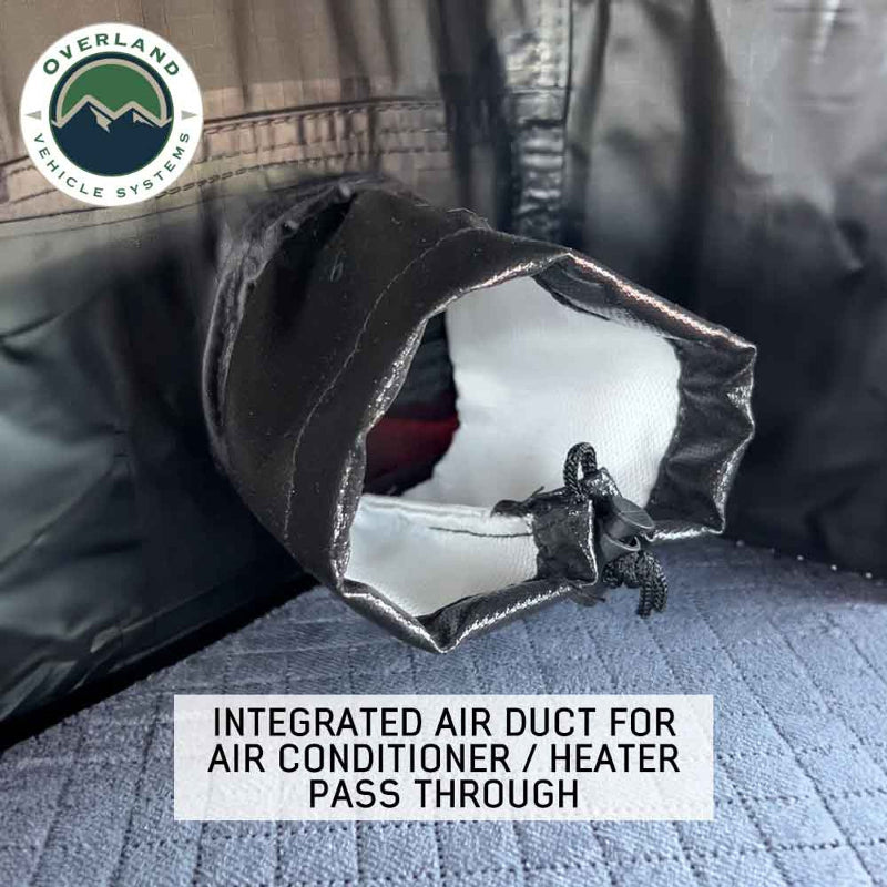 Image of Overland Vehicle Systems rooftop tent featuring an integrated air duct for air conditioner/heater pass-through, close-up view of the duct opening with black fabric edges on a blue mattress surface
