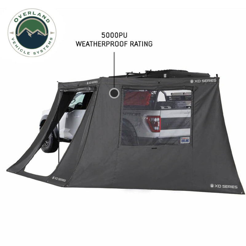Image of OVS XD Nomadic 180 LTE awning walls installed on a pickup truck, black waterproof fabric with large window panel and weatherproof rating callout, side view on a white background.