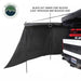 Image of OVS XD Nomadic 180 LTE awning wall panel deployed from a pickup truck, black blackout-coated fabric reducing light and heat, angled side view on a white background.