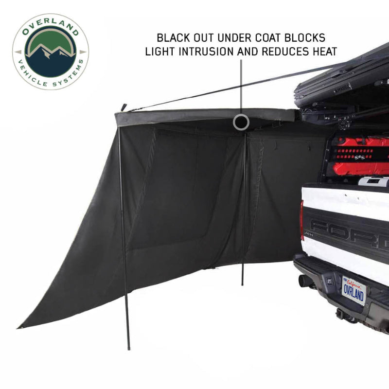 Image of OVS XD Nomadic 180 LTE awning wall panel deployed from a pickup truck, black blackout-coated fabric reducing light and heat, angled side view on a white background.