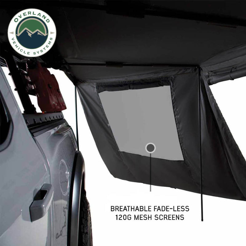 Image of OVS XD Nomadic 180 LTE awning wall interior showing breathable mesh window panel in black fabric, installed beside a pickup truck, angled close-up view on a white background.