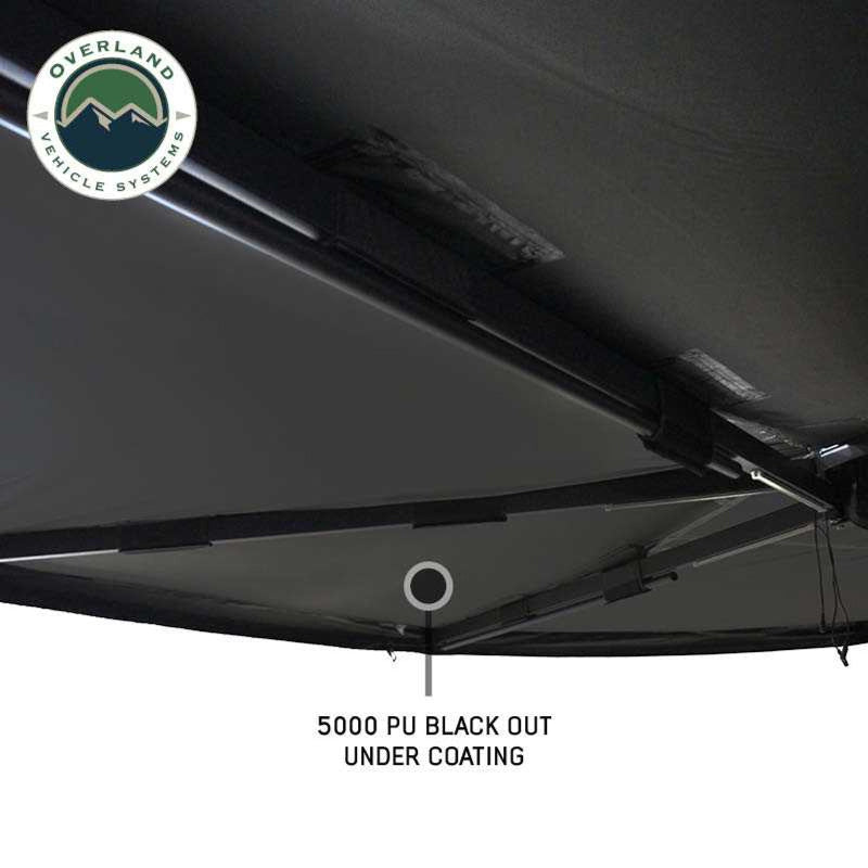 Image of a black 270-degree awning wall kit, showing a large window to allow a cross breeze, with the interior of a vehicle visible through the entry opening. The "Overland Vehicle Systems" logo is in the top left corner, all on a white background