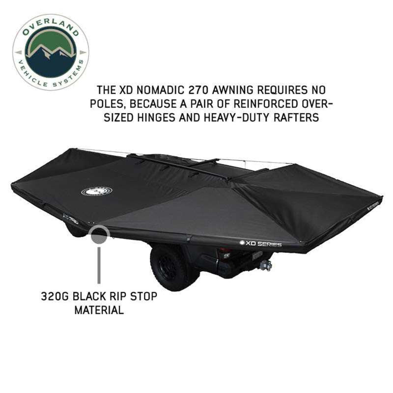 Image displaying a black XD Nomadic 270 awning, featuring 320G black rip stop material, shown partially open and mounted on a vehicle with its support structure visible underneath. The text indicates it requires no poles due to reinforced oversized hinges and heavy-duty rafters