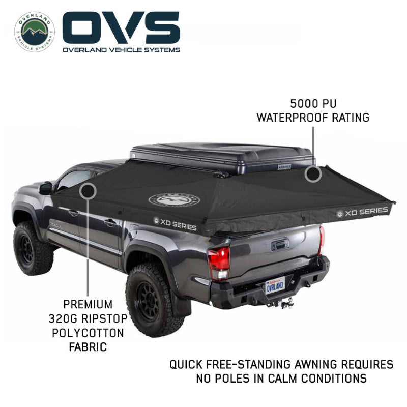 Image of an OVS XD Nomadic 270 LTE awning deployed from a pickup truck, black ripstop polycotton fabric with 5000 PU waterproof rating, shown freestanding in angled rear and side view on a white background.